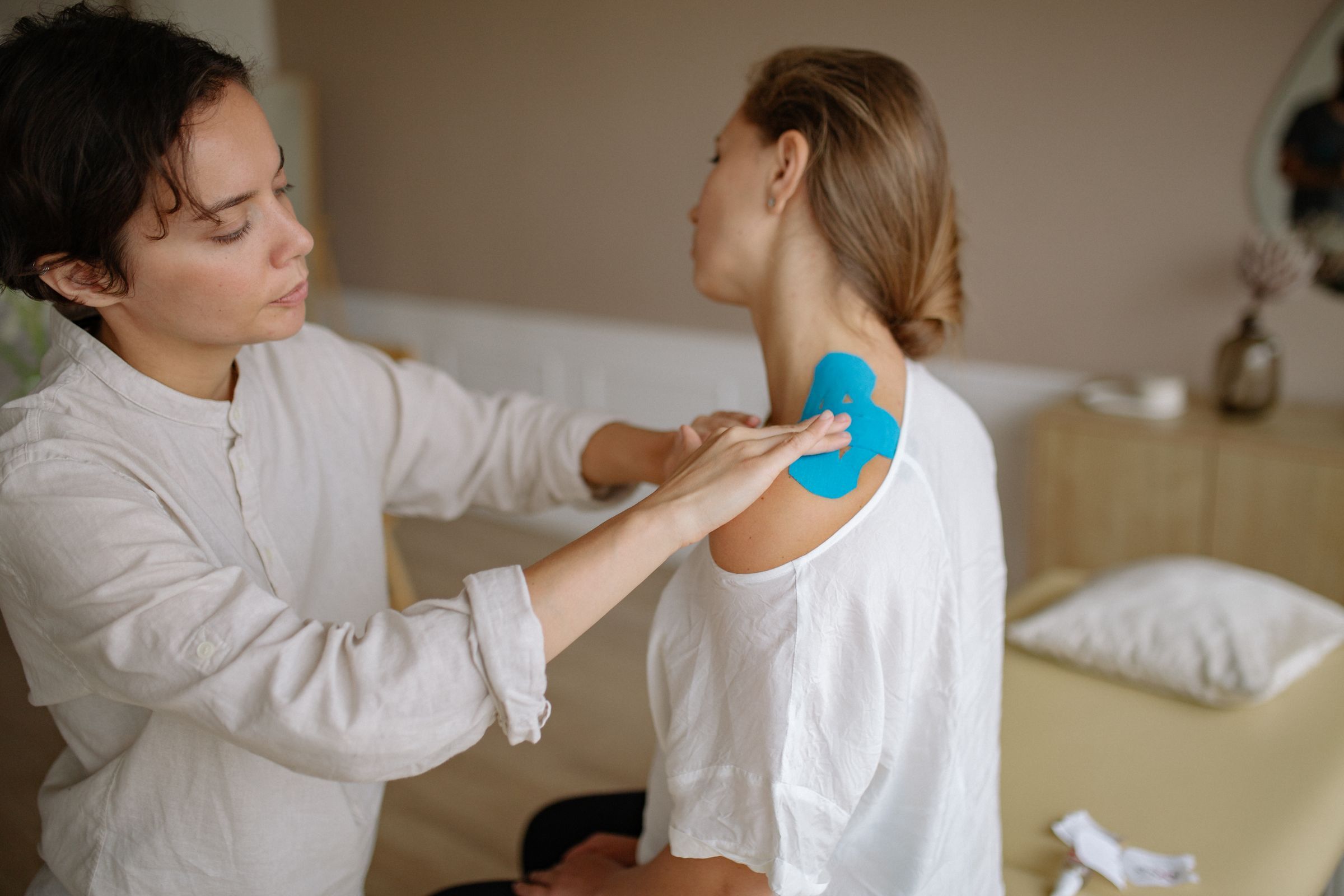 A physiotherapist applies tape to a client's shoulder