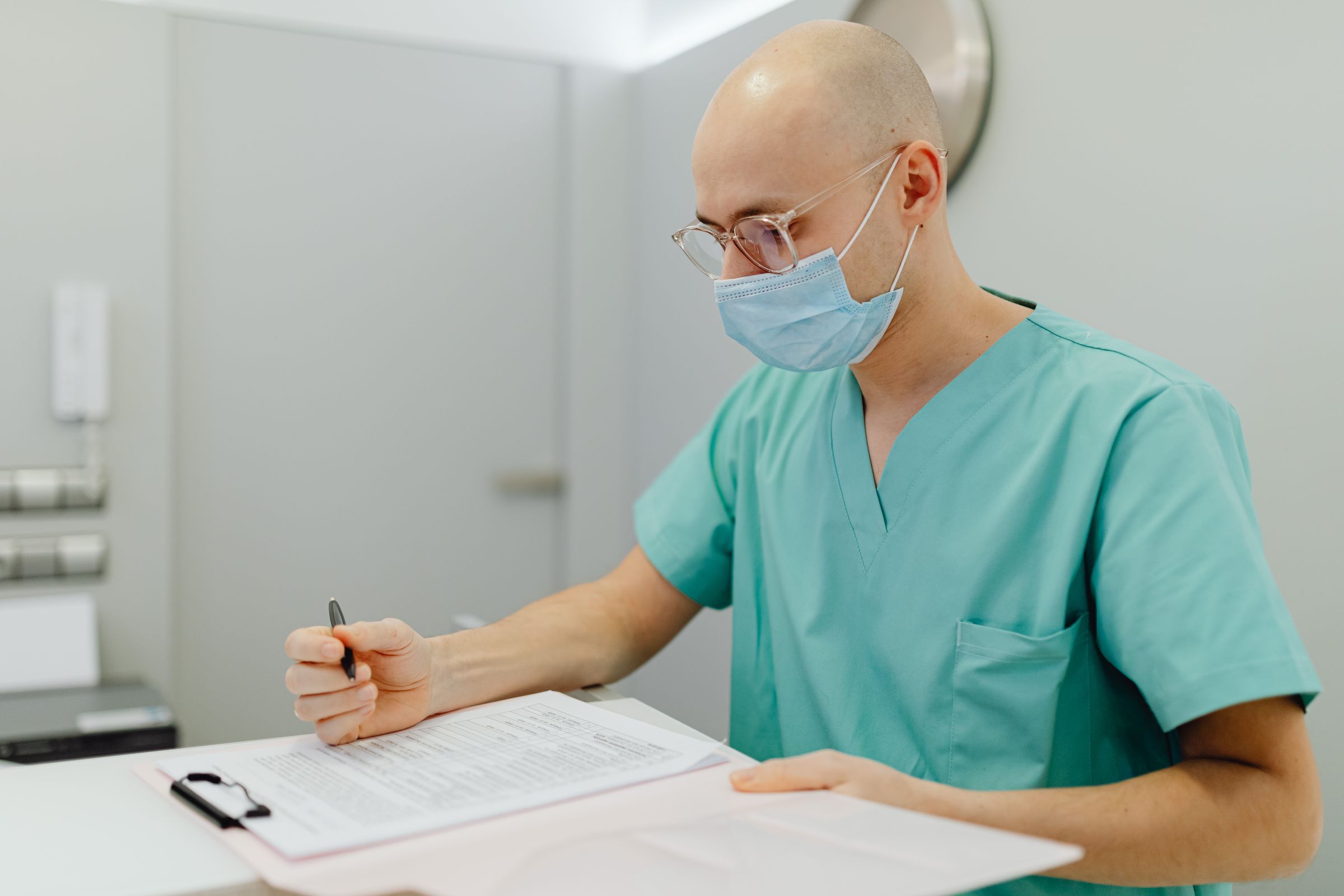 A specialist in scrubs reviews notes at the desk in his rooms